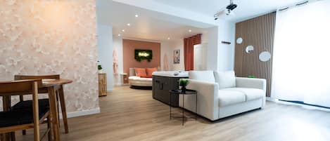 A modern living room with a sofa, a coffee table, and a dining area with a wooden table and chairs.