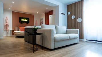 A modern living room with a sofa, a small table with a plant, and a wooden floor.