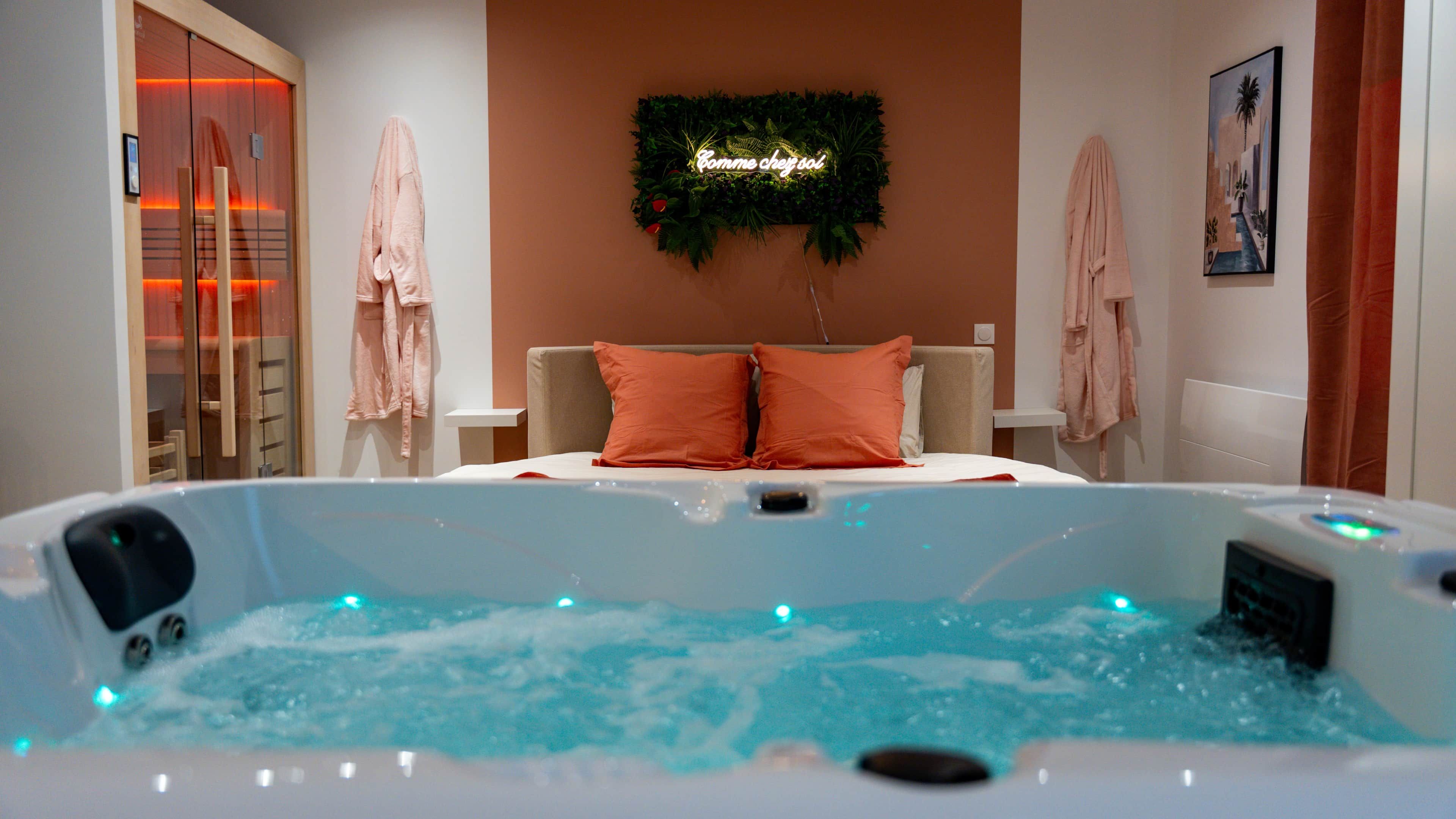 A spa room with a hot tub, two orange pillows, a neon sign, and a painting on the wall.