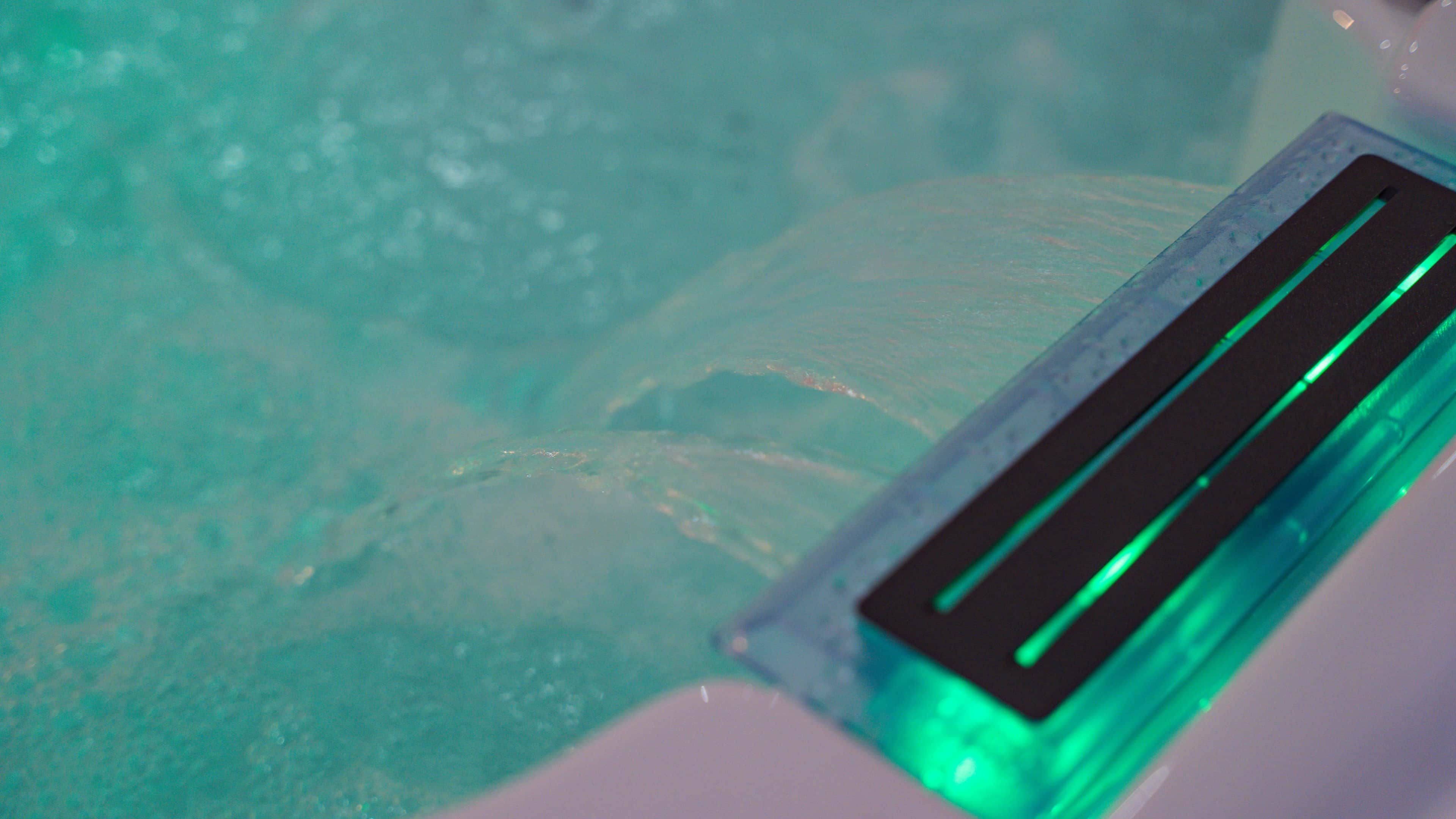 A bathtub with a green light strip and a black object inside.