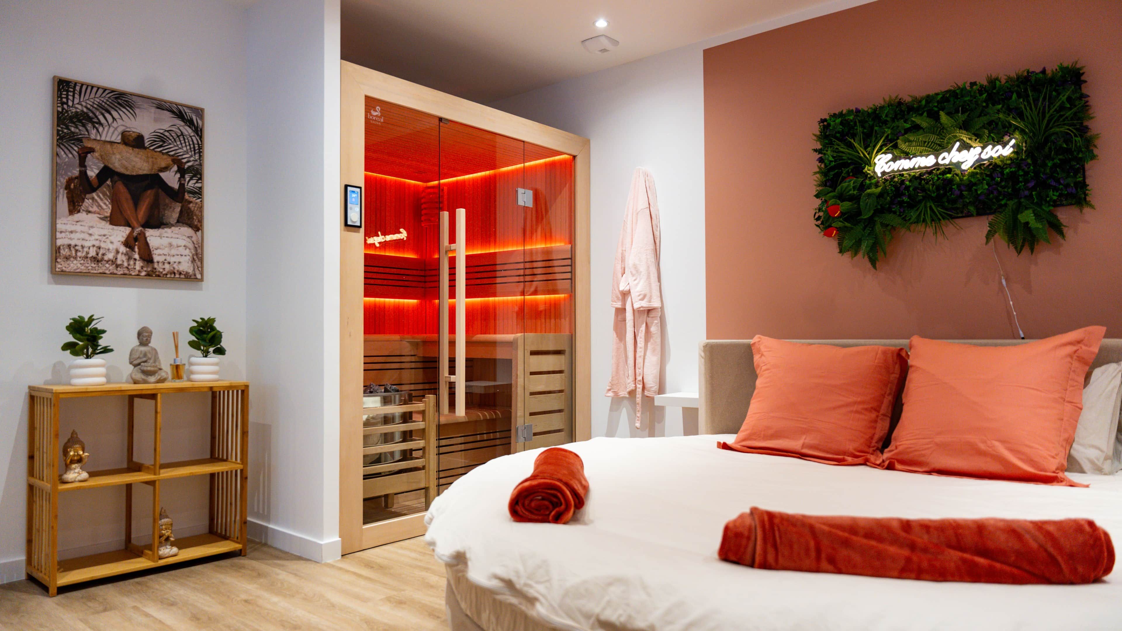 A hotel room with a bed, a wooden console table with decorative items, a red-lit walk-in closet, and a wall-mounted sign.