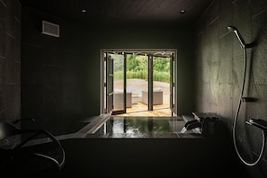 A spa room with a wooden floor, a large window, and a shower area.