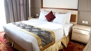 Una habitación de hotel con una cama grande, una mesita de noche y un cuadro colgado en la pared.
