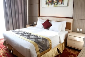 Quarto de hotel com uma cama grande, uma mesinha de cabeceira e um quadro pendurado na parede.