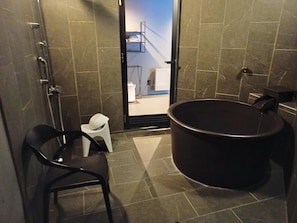 A bathroom with a bathtub, a toilet, and a chair.
