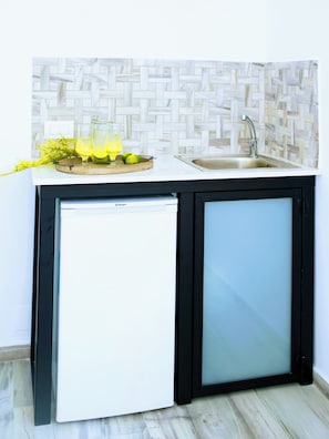 Cozinha compacta com geladeira embutida, pia e bancada com painel de fundo trançado.