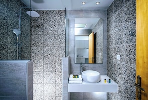 Une salle de bain moderne équipée d’une douche, d’un lavabo avec des articles de toilette et d’un miroir.