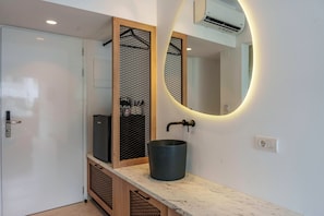 Uma casa de banho moderna com porta branca, lavatório preto e espelho redondo com iluminação embutida.