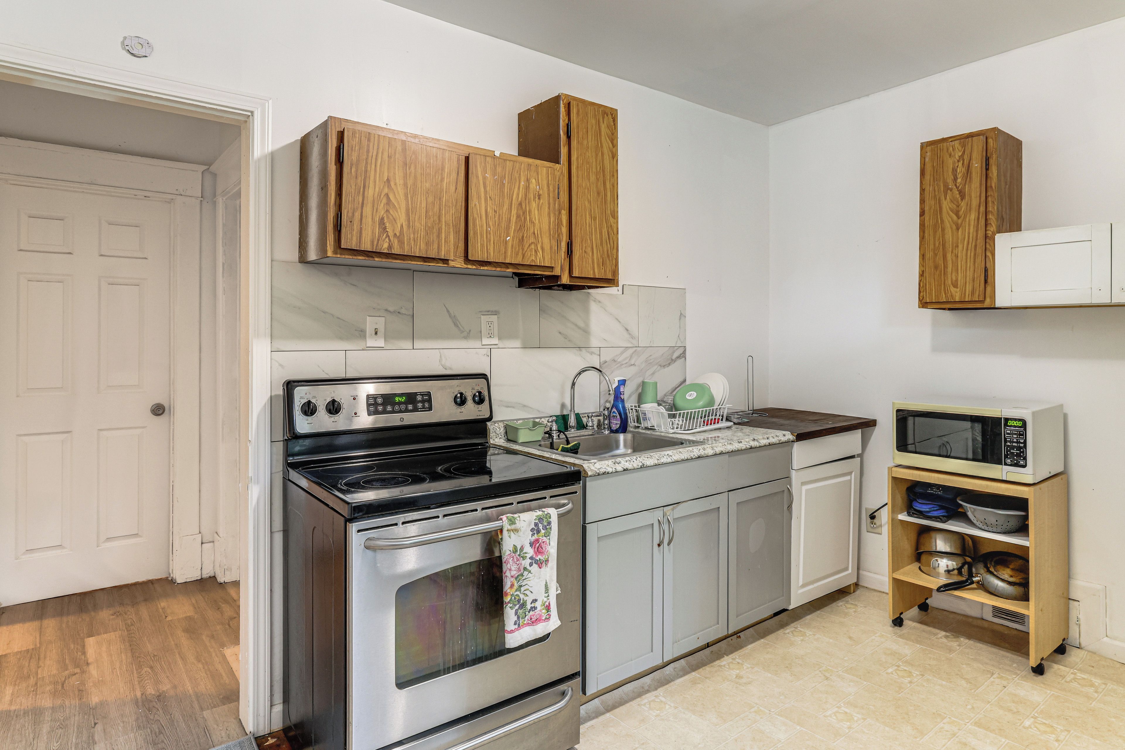 Une cuisine de taille réduite, équipée d’une cuisinière, d’un four, d’un évier et de meubles de rangement en bois.