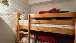 Ein Stockbett mit Holzrahmen, einer Matratze und einem Kopfkissen.