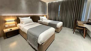 Una habitación de hotel moderna con dos camas, un escritorio y un ventilador de techo.