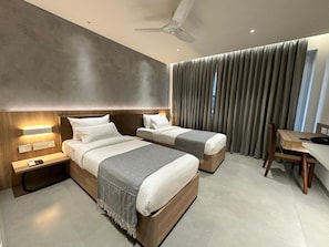 Una habitación de hotel moderna con dos camas, un escritorio y un ventilador de techo.