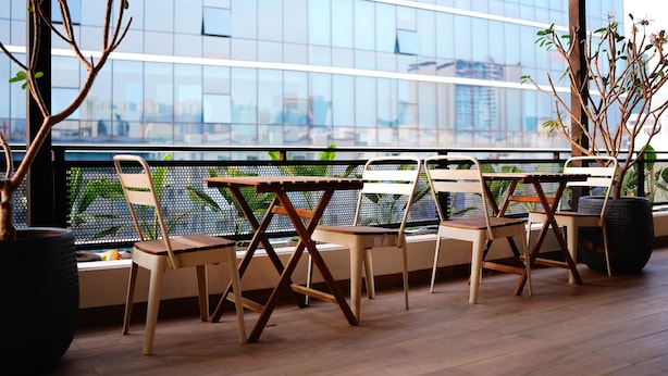 Un área de estar moderna al aire libre con vista a un edificio de vidrio.