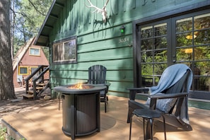 A green building with a fire pit, outdoor seating, and a staircase leading to an upper level. - Hotevilla Hideaway, Cozy Cabin Retreat (Flagstaff)