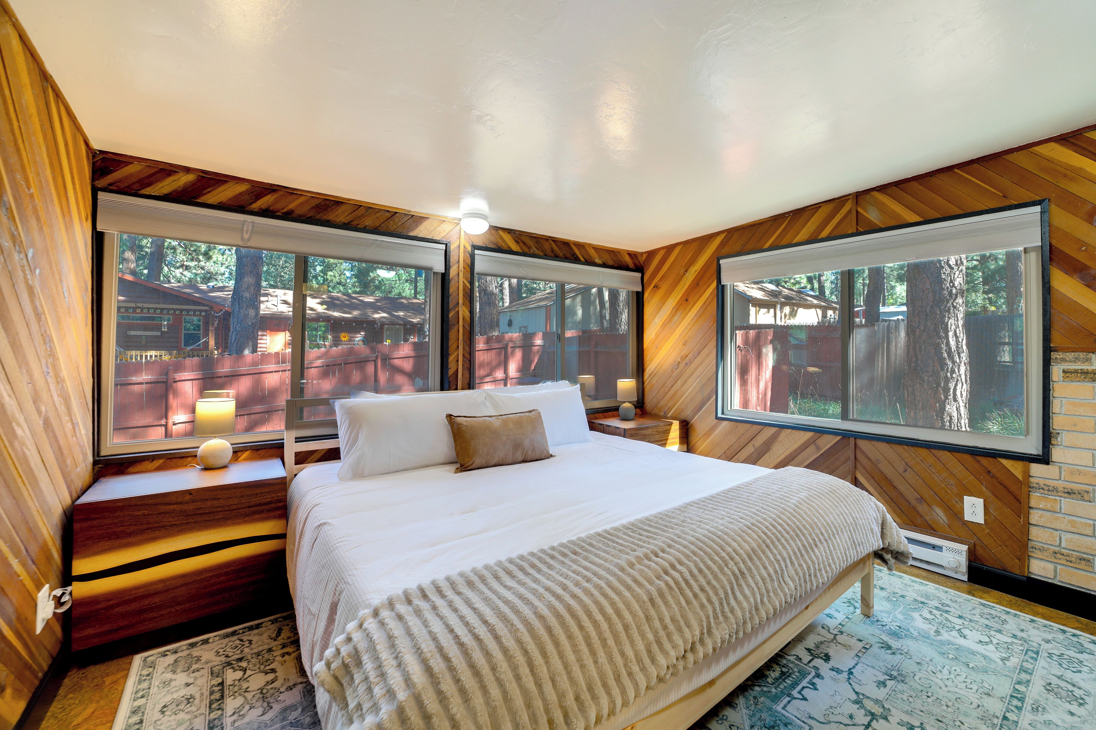 A bedroom with a large bed, two bedside tables, a window, and a view of the outdoors.