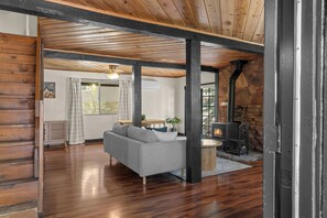 A log cabin interior with a living area featuring a sofa, a fireplace, and a stone wall. - Hotevilla Hideaway, Cozy Cabin Retreat (Flagstaff)