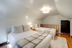 A bedroom with two beds, a wooden headboard, a nightstand, a lamp, and a door. - Hotevilla Hideaway, Cozy Cabin Retreat (Flagstaff)