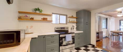 Una cocina con piso a cuadros, electrodomésticos integrados y estantes de madera.