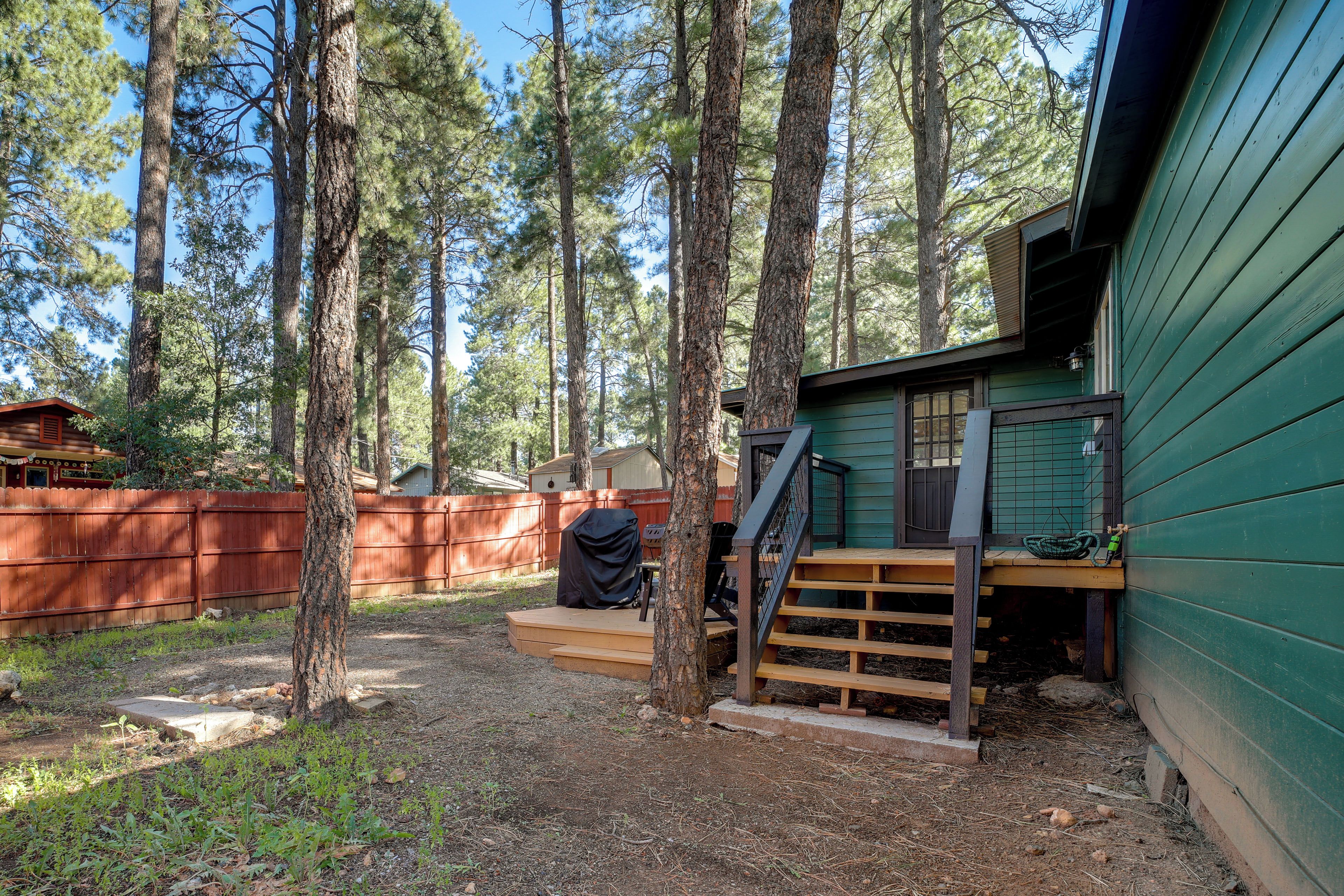 A cabin with a wooden deck, a covered grill area, and a staircase leading to the main building.