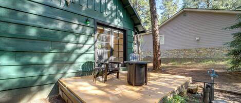 A wooden deck with a table and chairs, a stone wall, and a building with a green facade.
