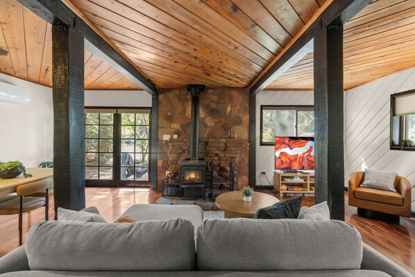 A cozy living room with a stone fireplace, a television, and a comfortable seating area. - Hotevilla Hideaway, Cozy Cabin Retreat (Flagstaff)