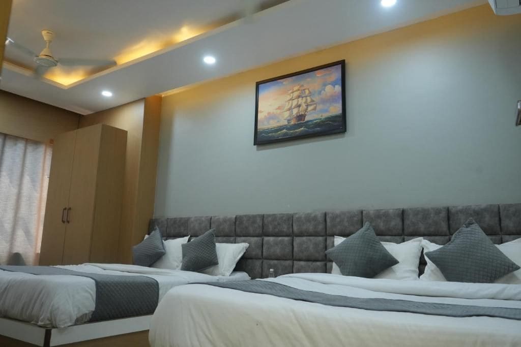 A hotel room with two beds, a large painting of a ship on the wall, and a ceiling fan.