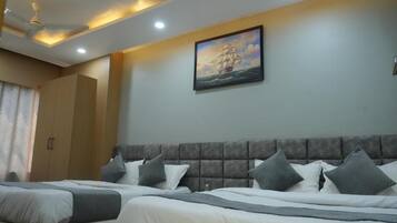 Une chambre d’hôtel avec deux lits, un grand tableau représentant un navire accroché au mur et un ventilateur de plafond.