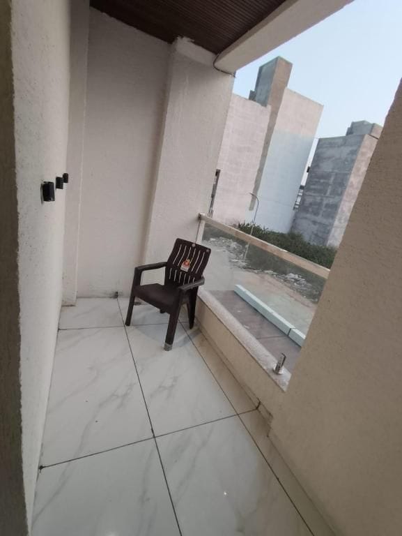 A balcony with a chair, a tiled floor, and a view of buildings.