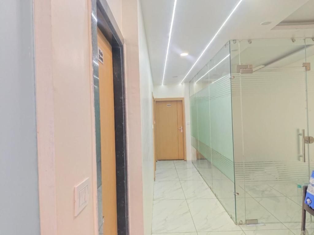 A hallway with a door, a glass partition, and a tiled floor.