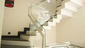 Una escalera moderna con barandas de vidrio y un objeto rojo colgando del techo.