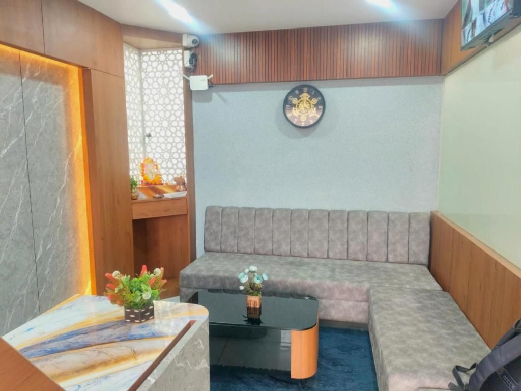 A room with a sofa, a coffee table, a decorative wall clock, and a small shelf with items.