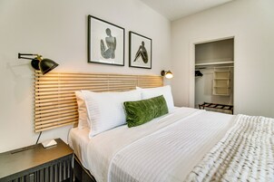 A neatly made bed with a wooden headboard, a green pillow, and a white comforter. There are two framed artworks on the wall above the bed.