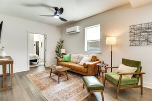 A modern living room with a brown leather sofa, a green armchair, a coffee table, and a ceiling fan.