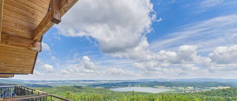 A wooden balcony with a view of a lake and forested landscape.