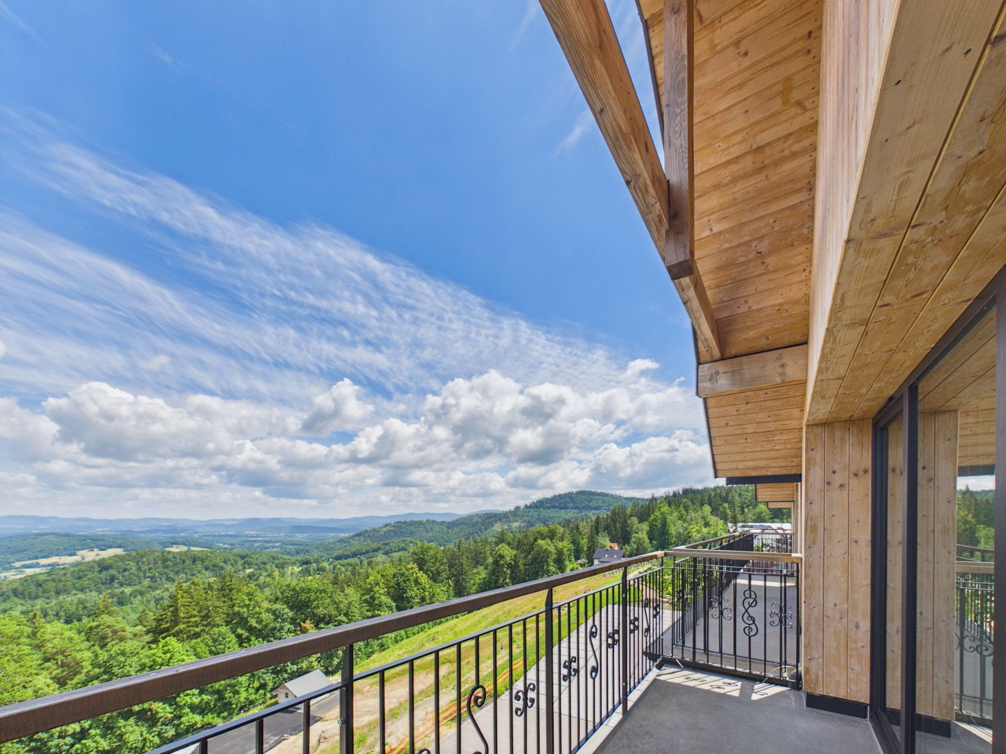 A balcony with a view of a forested valley and distant hills.