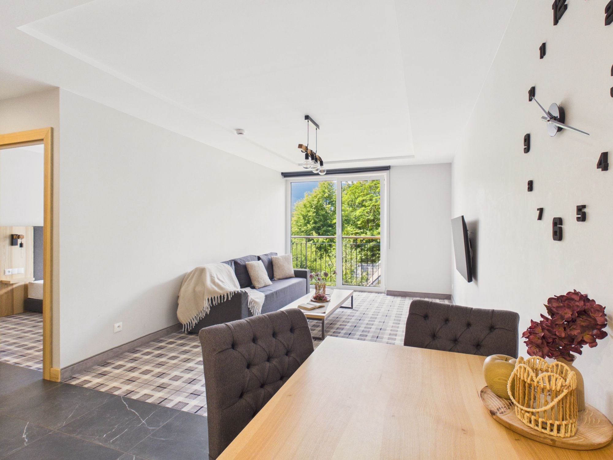 A modern living room with a sofa, a dining table, and a large window.