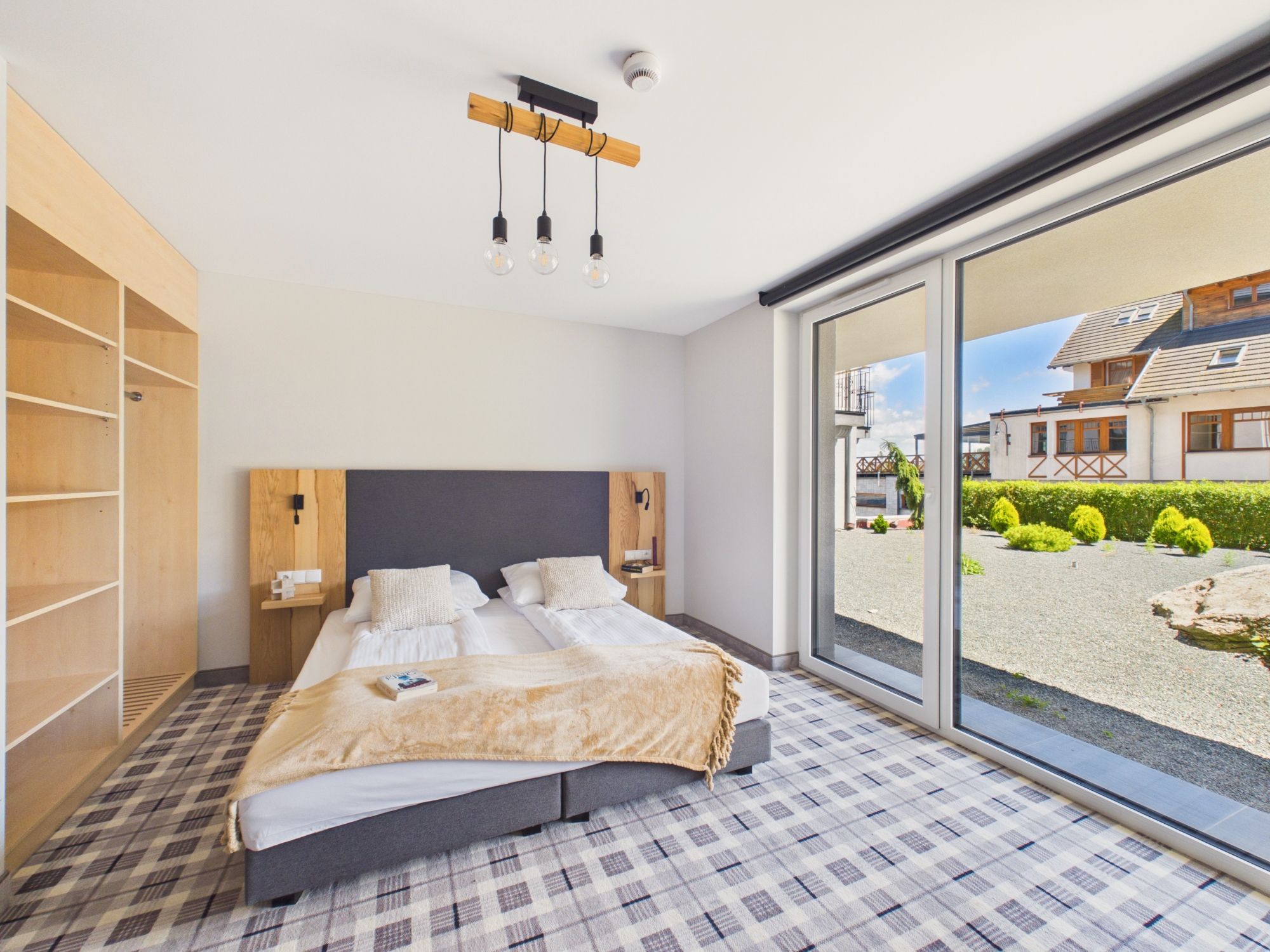 Un dormitorio con una cama grande, un armario de madera, una mesita de noche y vistas al exterior.