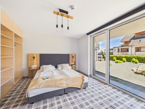 A bedroom with a large bed, a wooden wardrobe, a bedside table, a nightstand, and a view of the outside. - Kazalnica Family & Conference Resort with Pool & Restaurant by Solarento (Sosnówka)