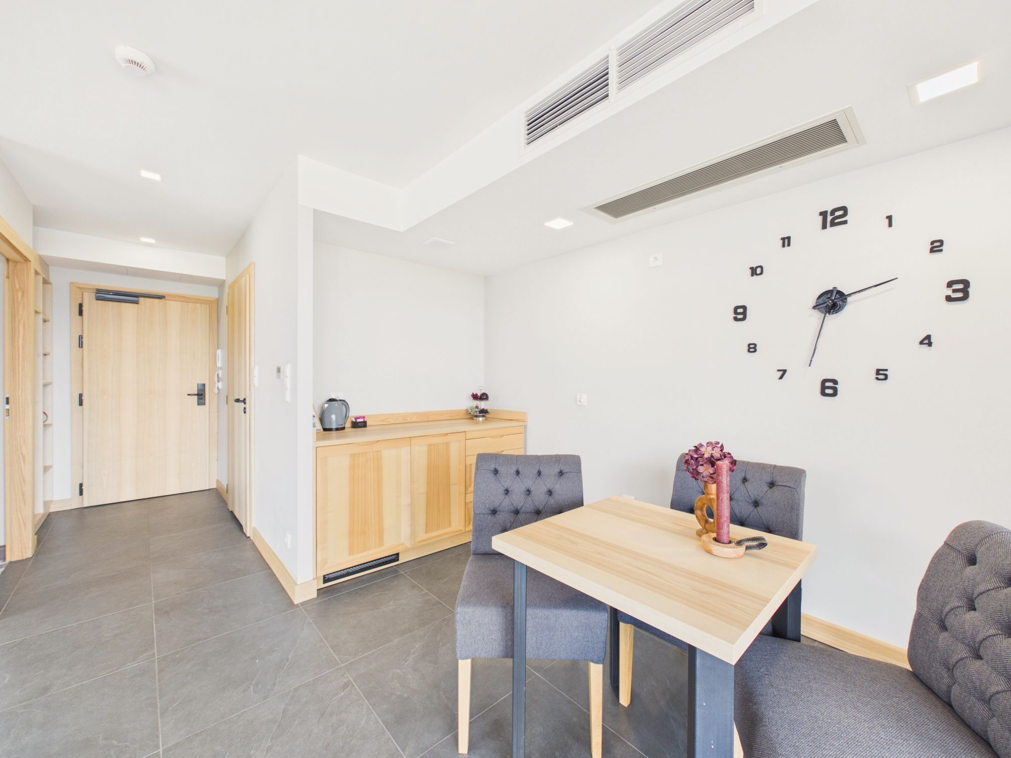 A modern kitchen with a wooden cabinet and a wall clock.
