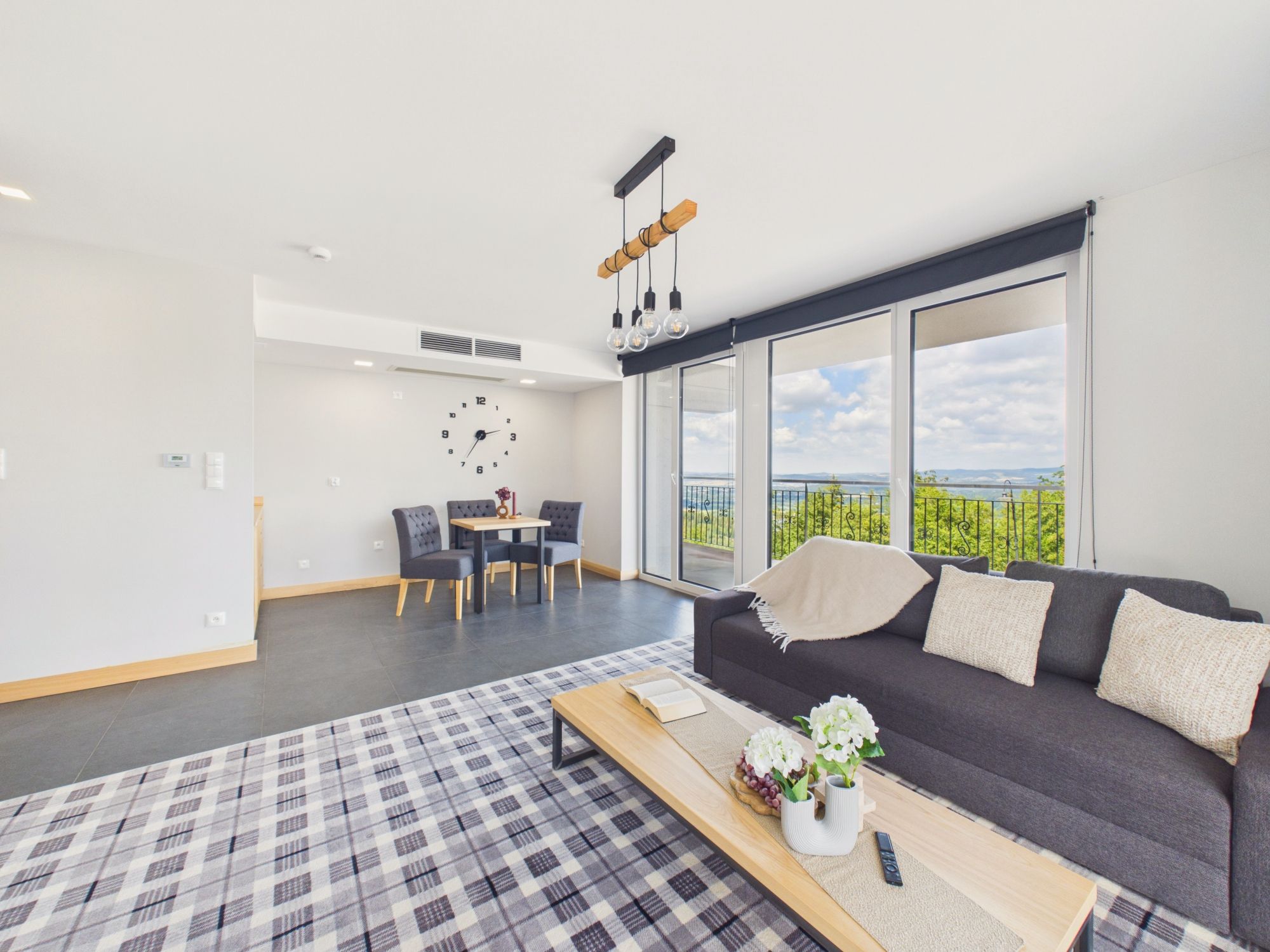A modern living room with a sofa, a coffee table, and a dining area with chairs and a table.