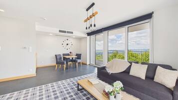 A modern living room with a sofa, a coffee table, and a dining area with chairs and a table.
