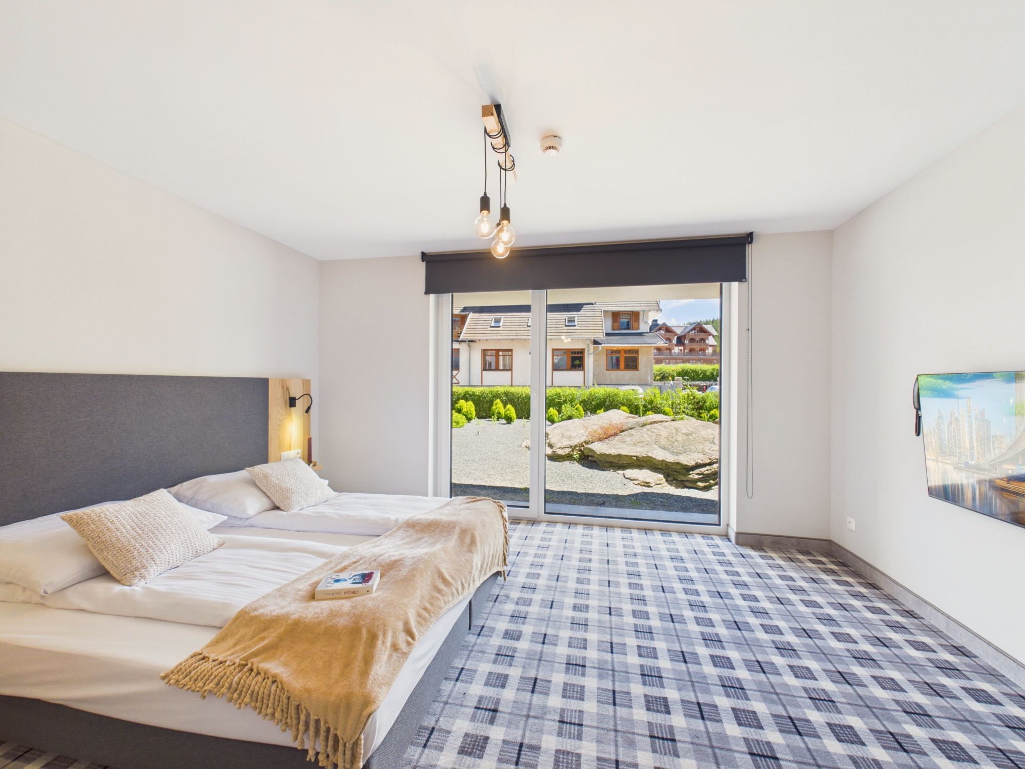 A bedroom with a bed, a window, and a view of a building.