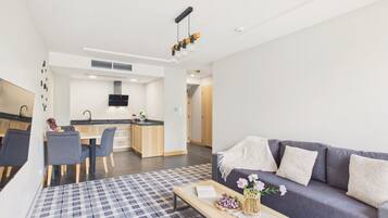 Een modern appartement met een eethoek, kitchenette en een woonkamer met een bank en salontafel.