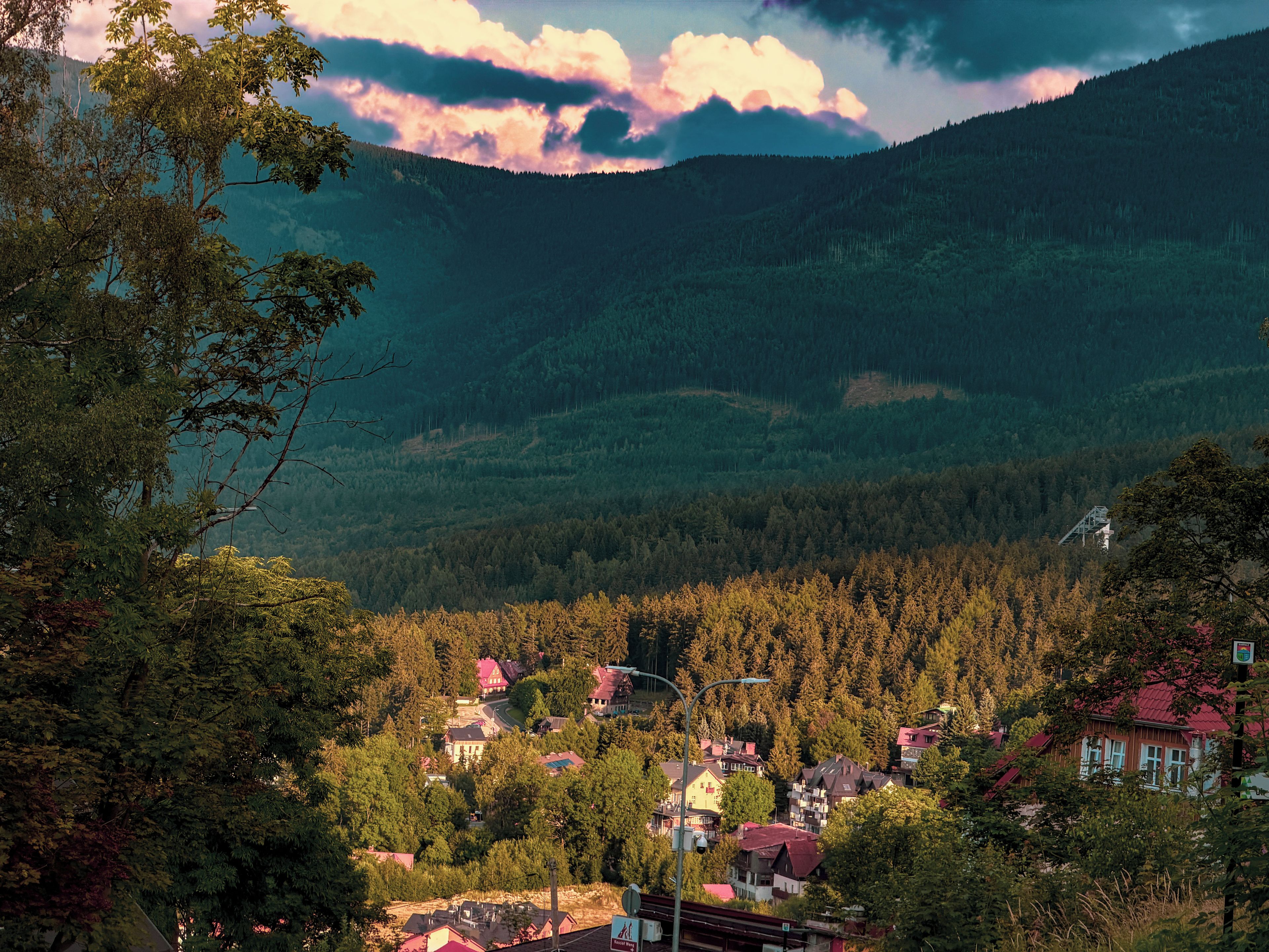 Paisagem montanhosa com uma pequena cidade situada entre as árvores.