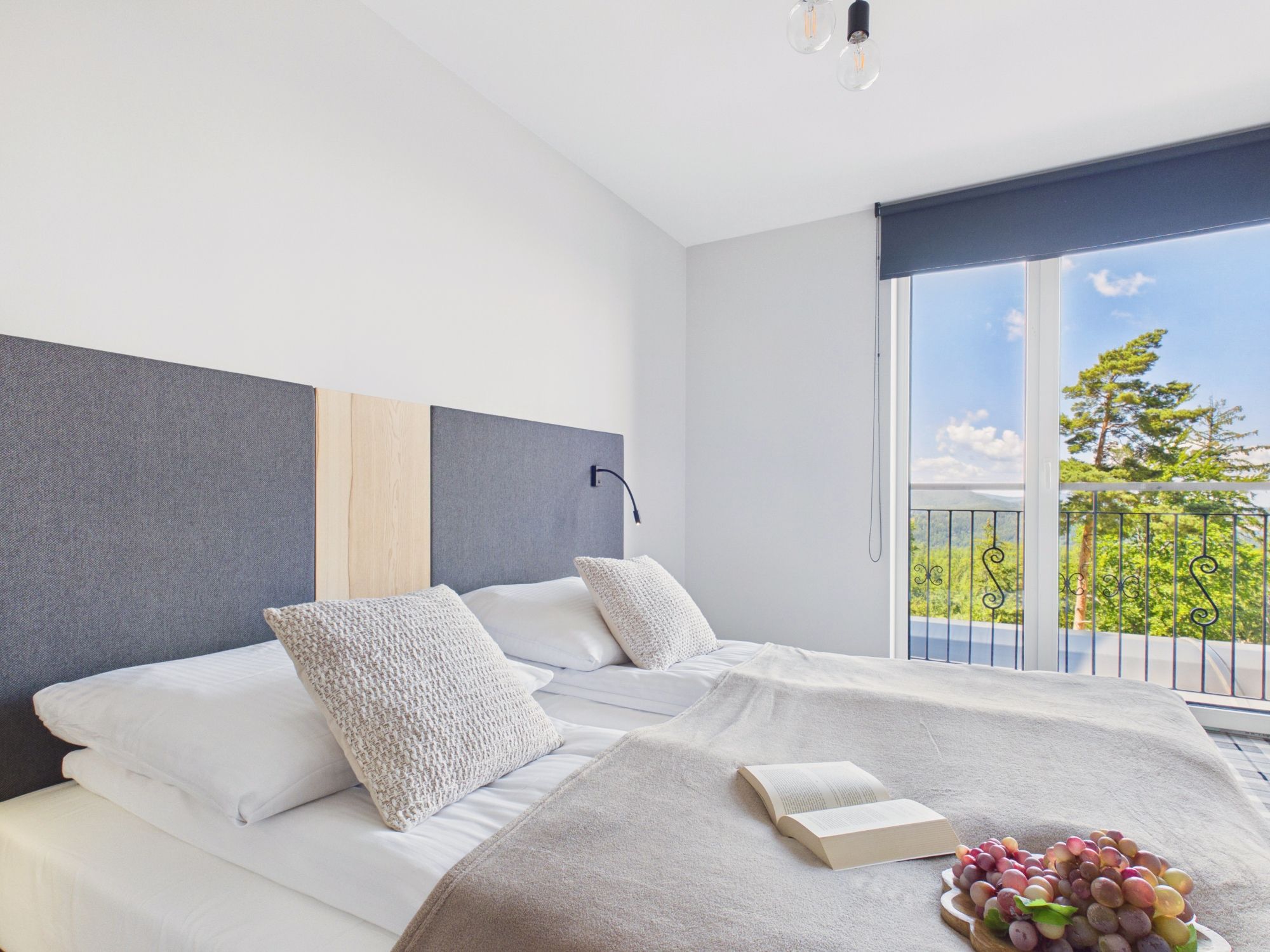 Un dormitorio moderno con una cama grande, vistas a la vegetación por la ventana y un balcón con barandilla.