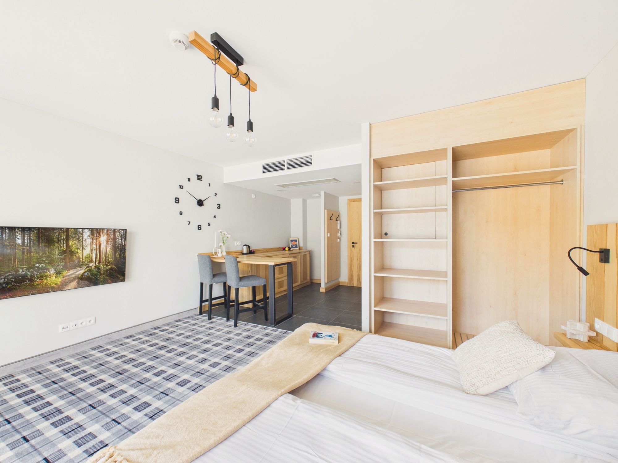 A modern bedroom with a bed, a desk, and a wardrobe.