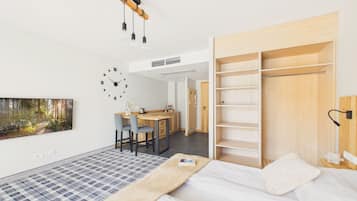 A modern bedroom with a bed, a desk, and a wardrobe.