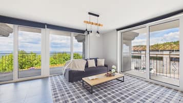A spacious balcony with a sofa and coffee table, large windows offering a scenic view, and a checkered floor.