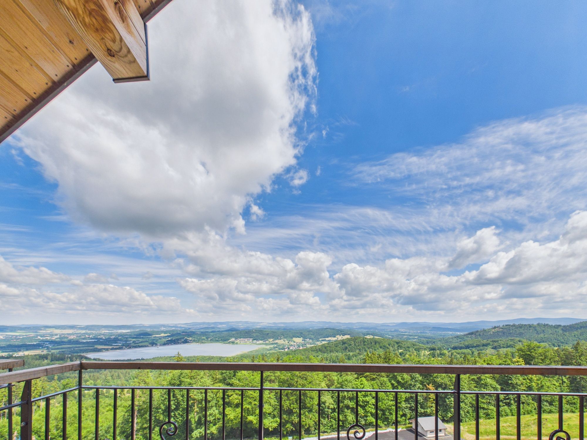 A balcony with a view of a lake and surrounding greenery.