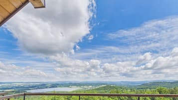 A balcony with a view of a lake and surrounding greenery.